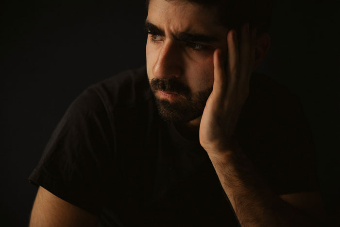 Man in a dark shirt looking pensive, suggesting feelings of low energy. Man in a dark shirt looking pensive, suggesting feelings of low energy.