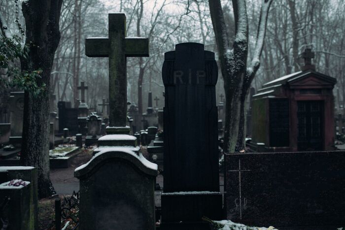 Gloomy cemetery with tombstones covered in snow, representing usual things that ended with the pandemic changes.