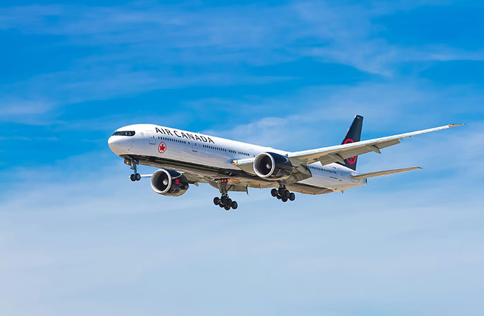 Air Canada plane in flight against blue sky representing airline travel. Air Canada plane in flight against blue sky representing airline travel.