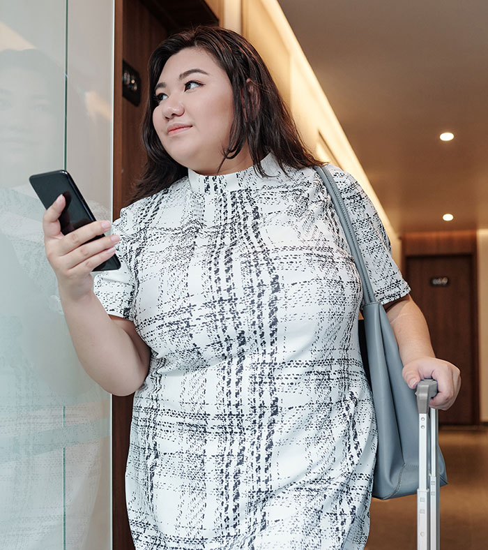 Woman holding phone and suitcase, related to seating issues on airplane. Woman holding phone and suitcase, related to seating issues on airplane.