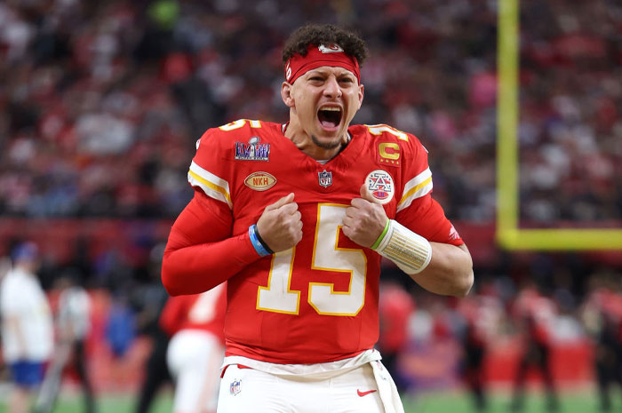 Football player Patrick Mahomes celebrating on the field, wearing a red jersey with the number 15, highlighting net worth and success.