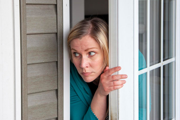 Woman looks cautiously out a door, concerned about strangers claiming to be half-siblings. Woman looks cautiously out a door, concerned about strangers claiming to be half-siblings.