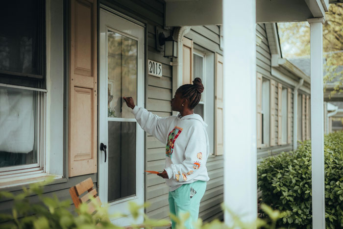 Woman answering door to strangers claiming to be half-siblings, outside suburban house. Woman answering door to strangers claiming to be half-siblings, outside suburban house.