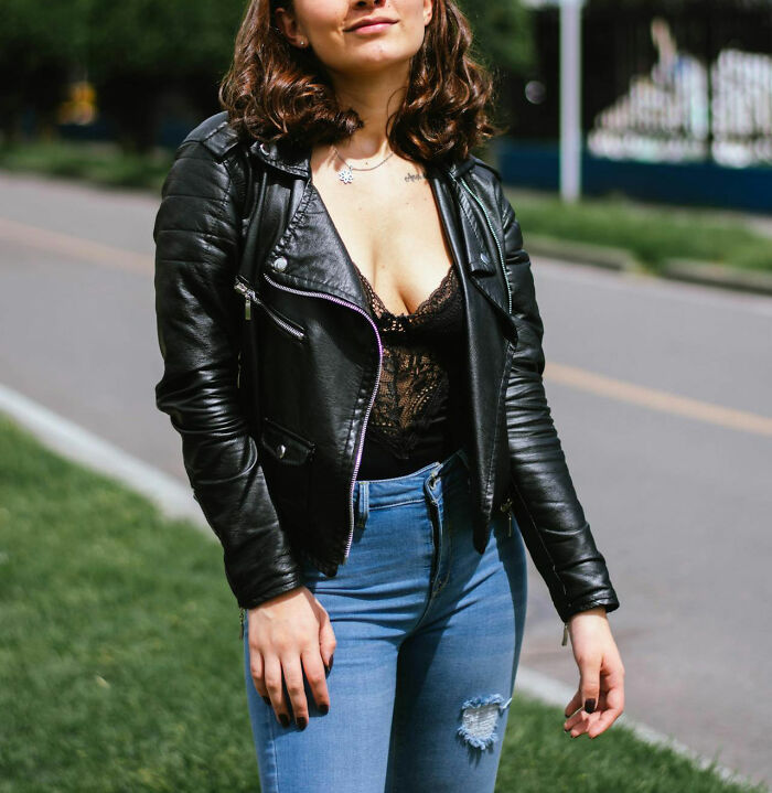Woman in a leather jacket and lace top standing by the street, reflecting common embarrassment issues women face.