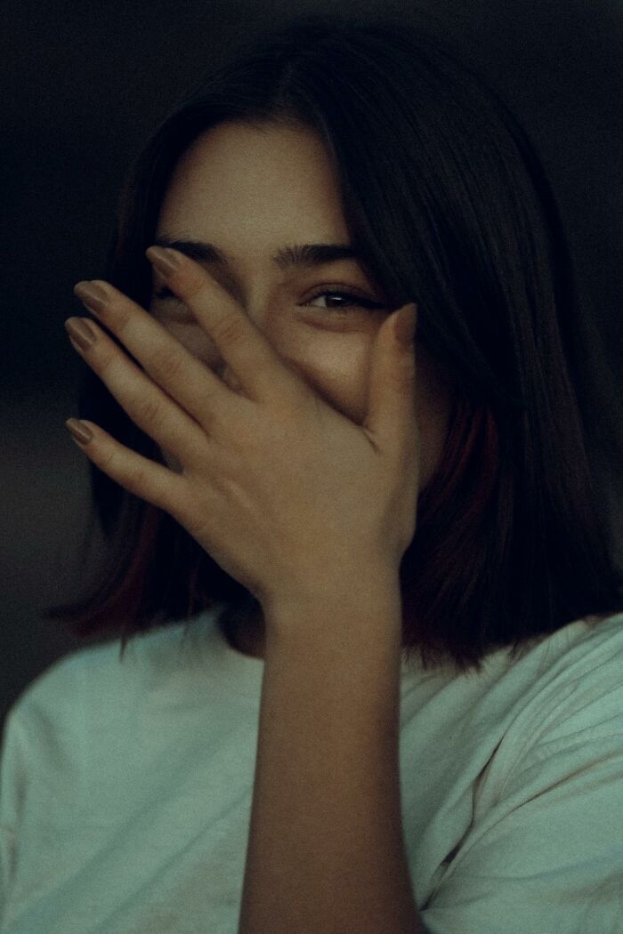 Woman covering her face with hand, reflecting embarrassment.