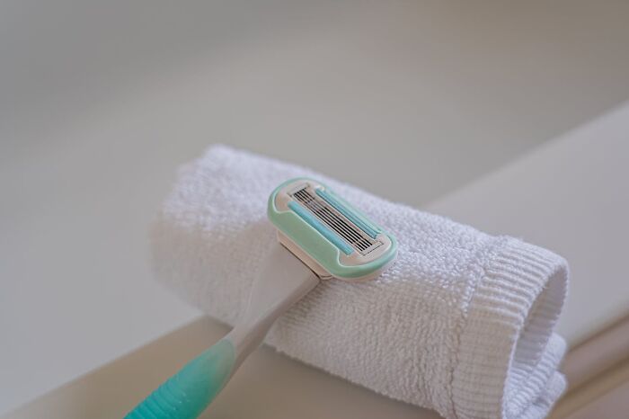 A shaving razor on a rolled white towel in a bathroom setting.