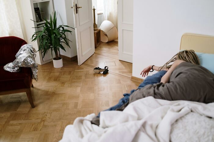 Person sleeping in a messy room, showcasing immature habits in adults in their 30s.