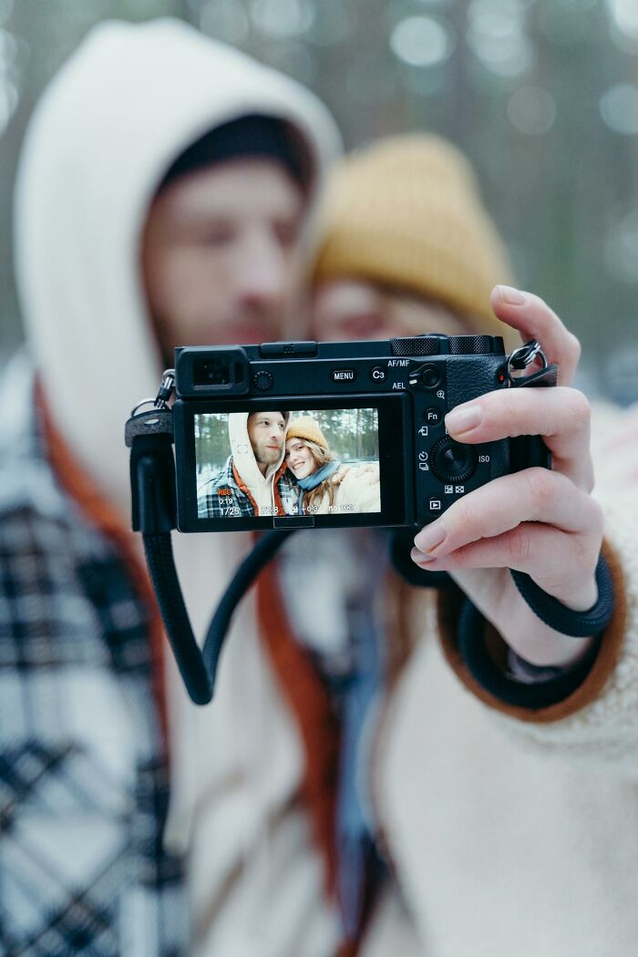 A couple taking a selfie with a camera in winter clothing, illustrating things that confuse men about women.