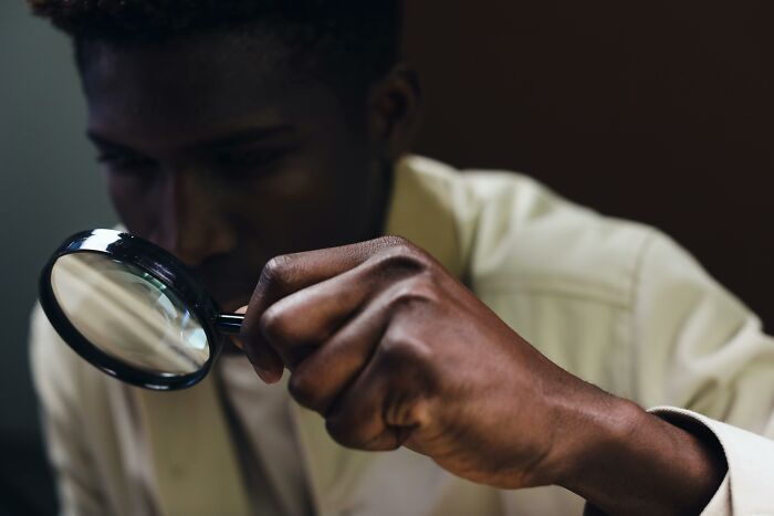 Person closely examining something with a magnifying glass to find differences. Person closely examining something with a magnifying glass to find differences.