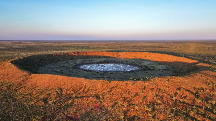 Aerial view of a massive crater landmark in a desert landscape during sunset. Aerial view of a massive crater landmark in a desert landscape during sunset.