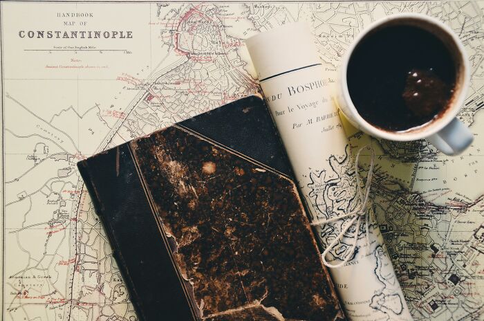 Old maps and a worn book placed next to a coffee cup, symbolizing countries and cities that got a rebrand. Old maps and a worn book placed next to a coffee cup, symbolizing countries and cities that got a rebrand.