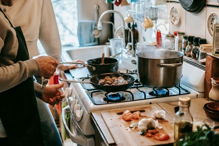 Adults cooking in a kitchen, demonstrating habits that might seem immature for their age.