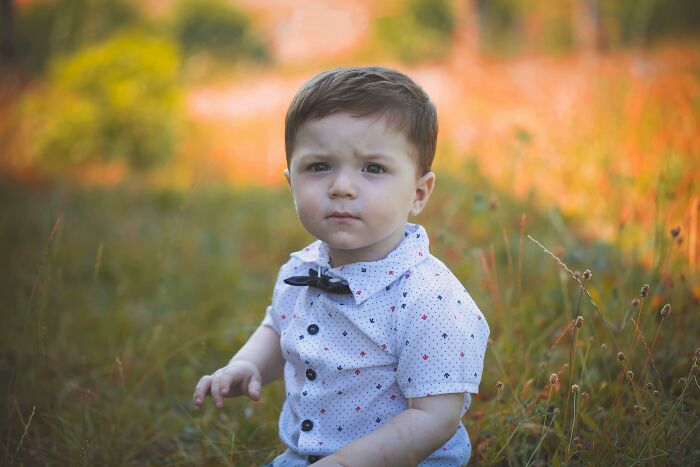 Young boy sitting in a field with a serious expression, reflecting on ghastly things told in church that made people quit.