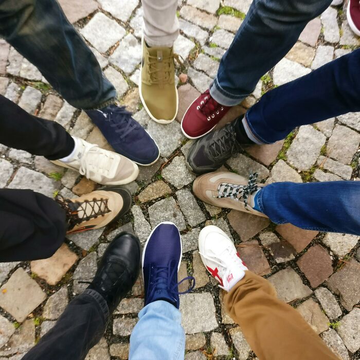 A circle of diverse shoes on cobblestones, symbolizing unity and sharing intrusive thoughts.