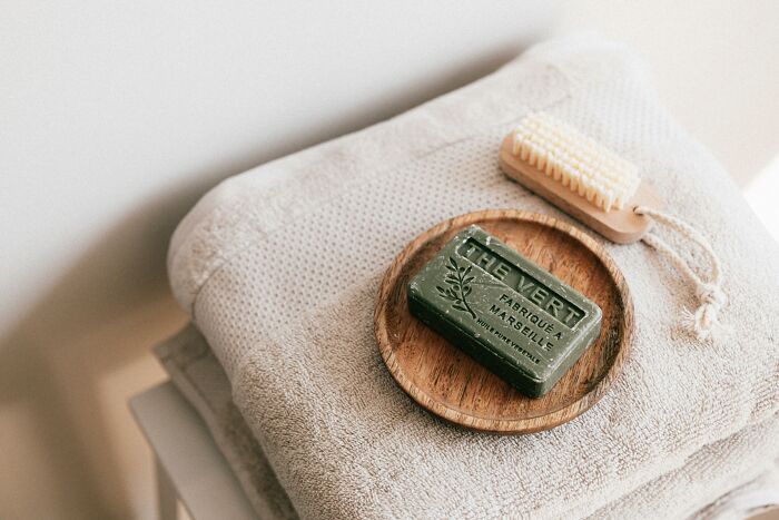 Bar of green soap with a brush on stacked towels, evoking calm and intrusive thoughts.