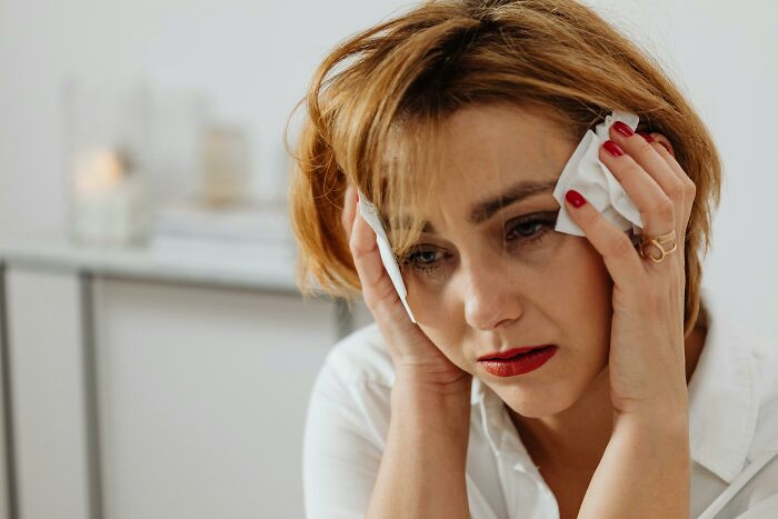 A woman looking distressed, holding tissues, potentially after an adult tantrum.