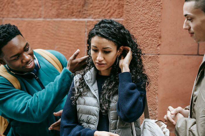A young woman showing distress while two friends try to console her, depicting people enduring unexplainable pain.