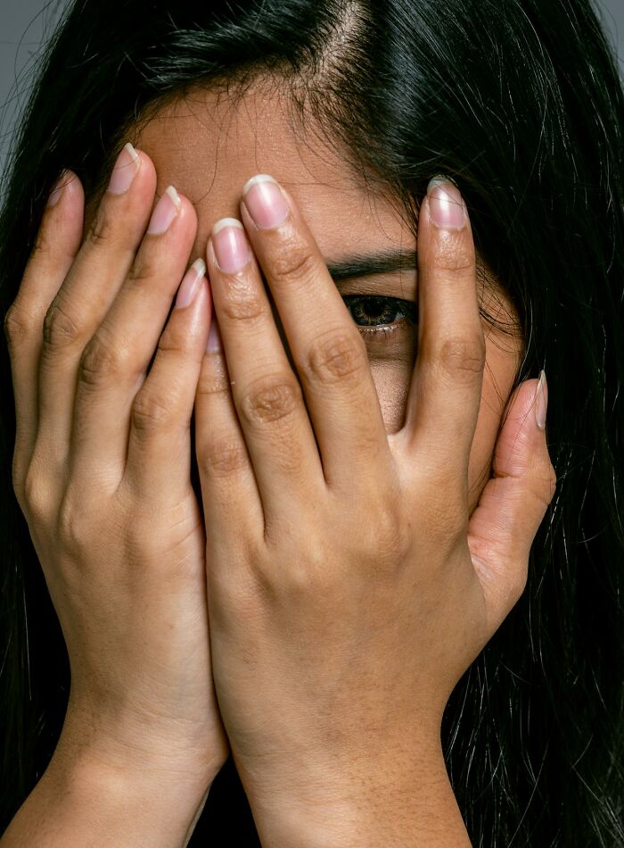 Woman covering her face with hands, illustrating embarrassment.