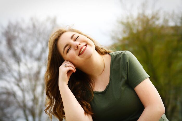 Smiling woman in a green shirt outdoors, enjoying an April Fool's moment.