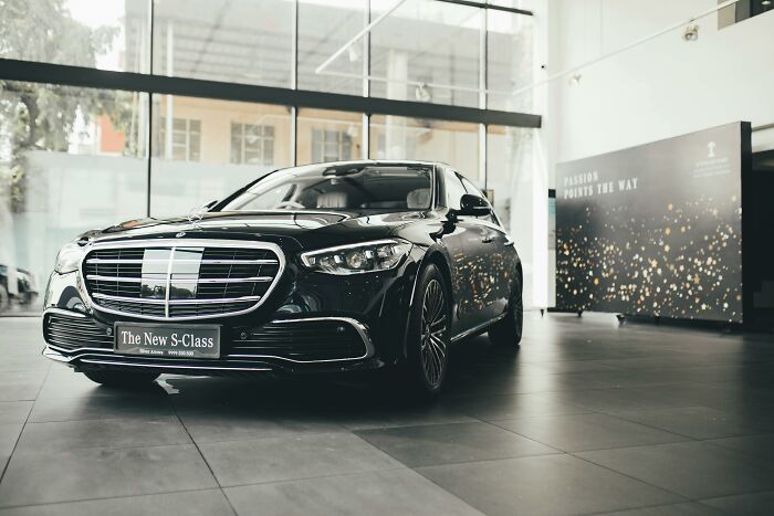 Luxury car showroom displaying a sleek black vehicle, symbolizing pretending to be rich.