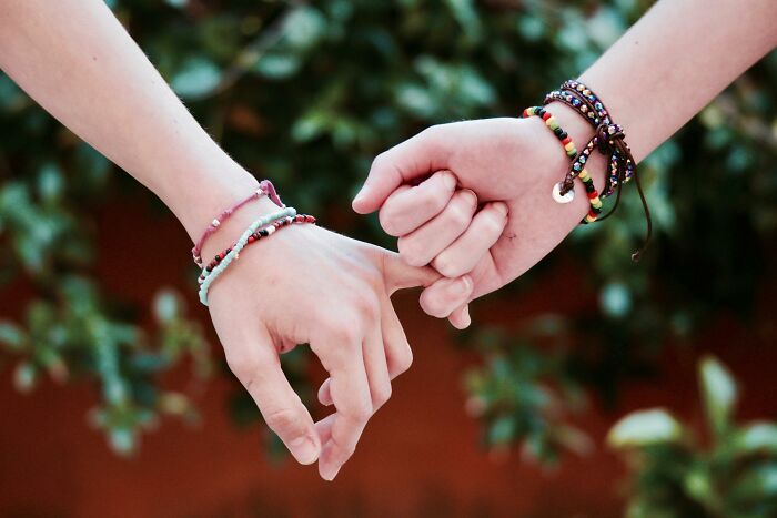 Two hands with bracelets gently touching, symbolizing attachment style and connection. Two hands with bracelets gently touching, symbolizing attachment style and connection.