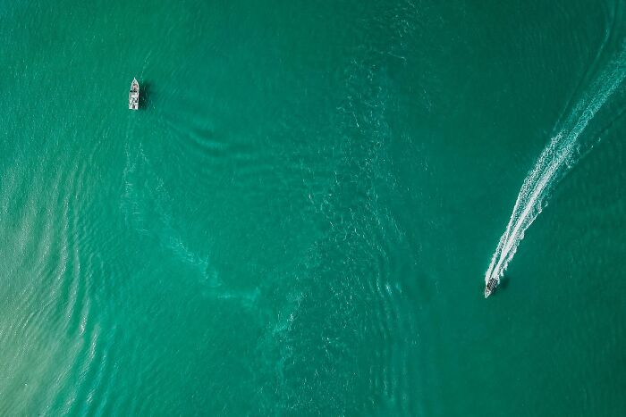 Aerial view of two boats on a turquoise sea, illustrating luxury and wealth.