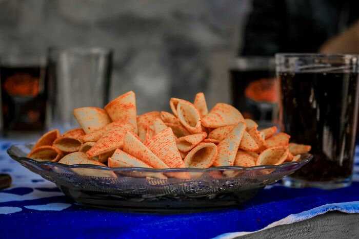 Plate of spicy rolled chips on a table with drinks, focusing on the shared experience.