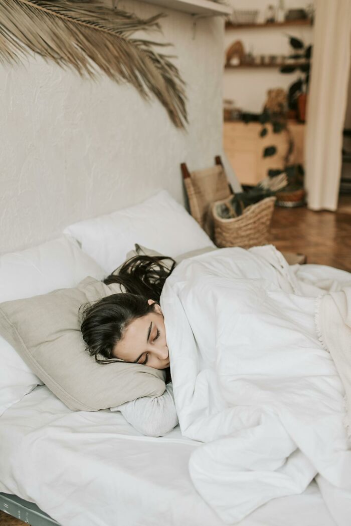 Woman sleeping peacefully in a cozy bed, capturing an intimate moment of rest.