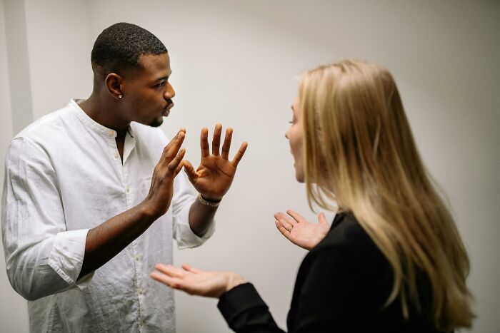 Man and woman animatedly discussing with absolute confidence in a bright room.