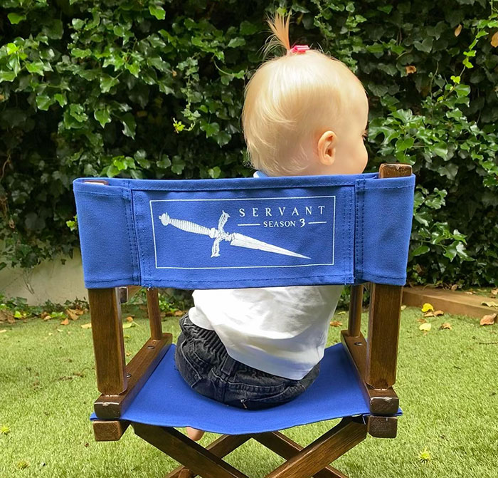 Baby sitting on a blue director's chair with "Servant Season 3" printed, outdoors on grass, related to Rupert Grint. Baby sitting on a blue director's chair with "Servant Season 3" printed, outdoors on grass, related to Rupert Grint.