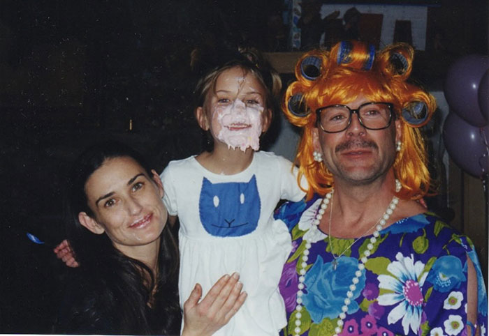 Demi Moore with a child and an adult in costume, featuring colorful attire and playful face paint. Demi Moore with a child and an adult in costume, featuring colorful attire and playful face paint.
