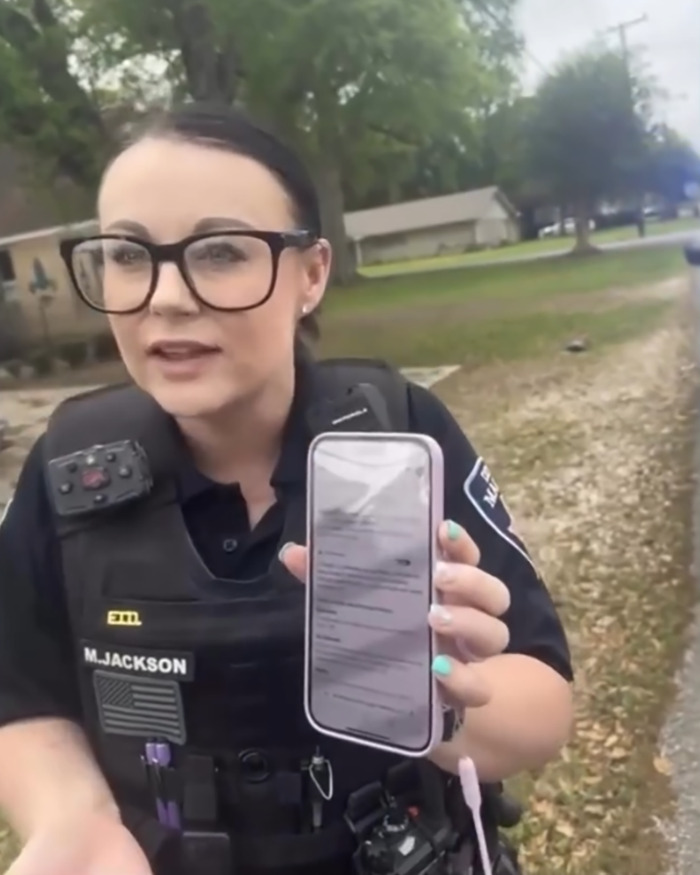 Police officer showing a phone screen during a street incident involving walking on the wrong side of the road. Police officer showing a phone screen during a street incident involving walking on the wrong side of the road.