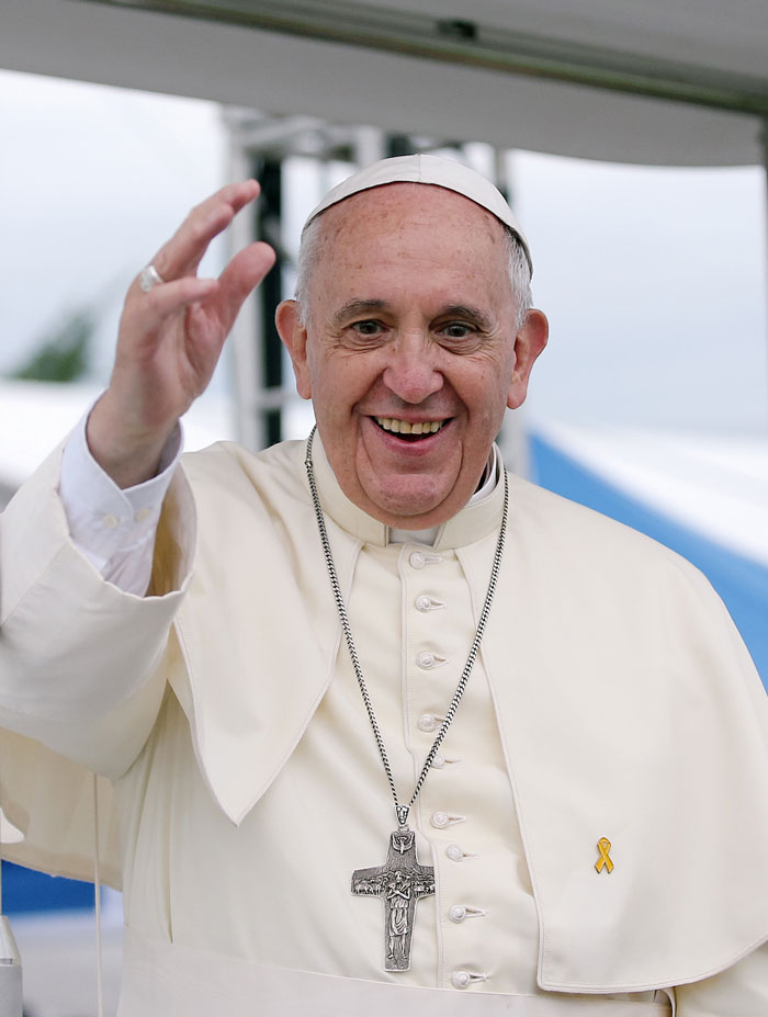 Pope Francis smiling and waving, dressed in white papal attire with a silver cross, greeting attendees in St. Peter’s Square. Pope Francis smiling and waving, dressed in white papal attire with a silver cross, greeting attendees in St. Peter’s Square.