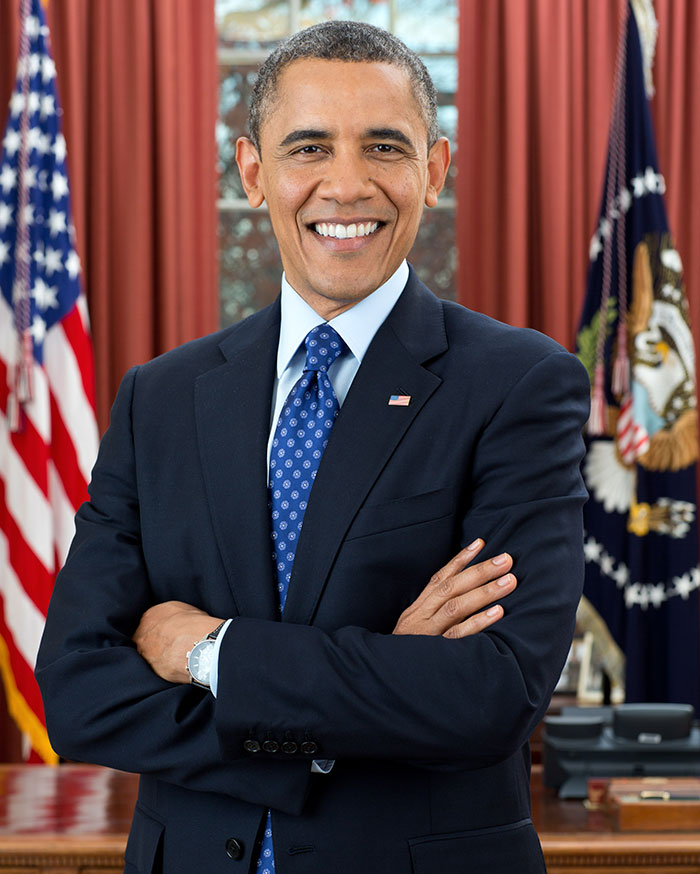 Barack Obama in a suit, standing with arms crossed and smiling confidently in an office setting. Barack Obama in a suit, standing with arms crossed and smiling confidently in an office setting.
