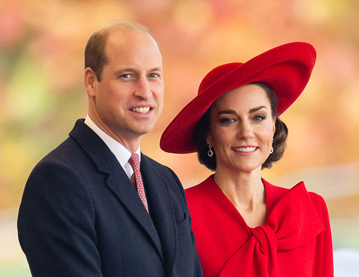 Prince William with companion in formal attire at a public event, against a colorful background. Prince William with companion in formal attire at a public event, against a colorful background.
