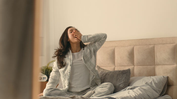 Person yawning on bed, illustrating unproductive morning routine.