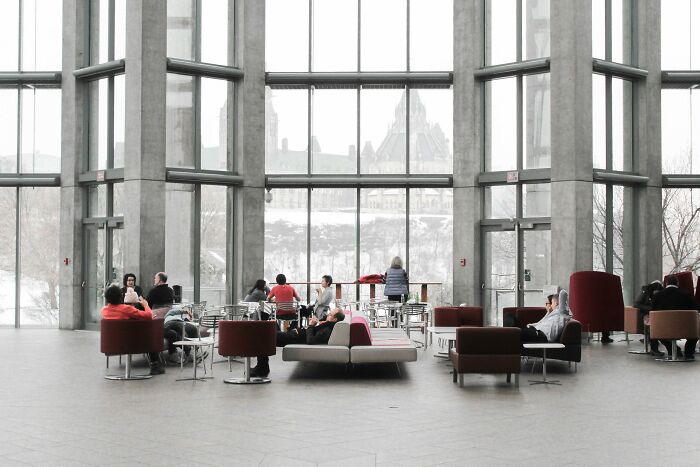 Modern lobby with people sitting in groups, large windows in the background, related to productivity tips discussion.