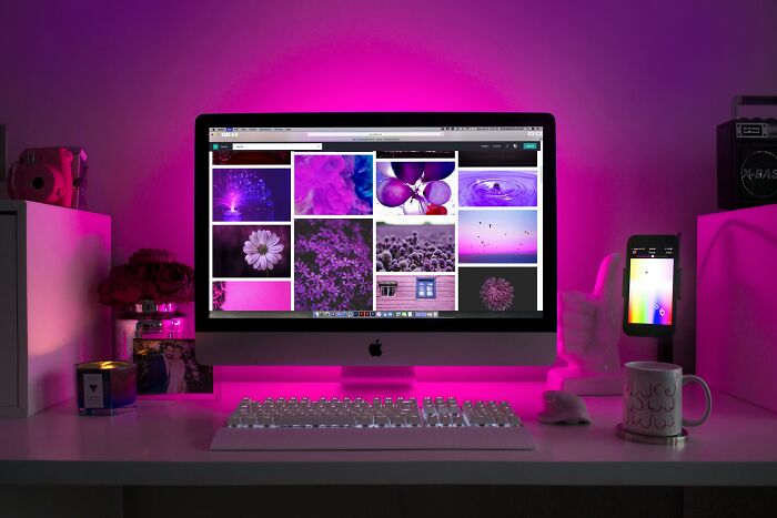 iMac displaying colorful images on a desk with pink lighting, emphasizing productivity tips.