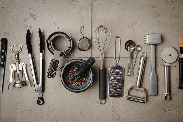 Assorted kitchen tools arranged on a stone surface, highlighting productivity tips in cooking.