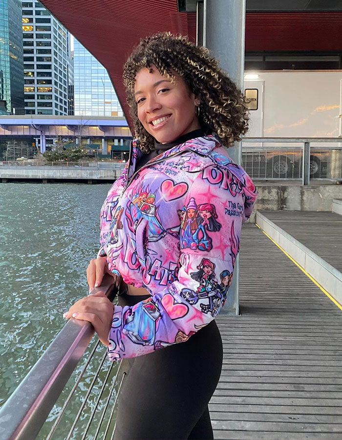 Smiling woman in colorful jacket by waterfront, standing outside near modern buildings. Smiling woman in colorful jacket by waterfront, standing outside near modern buildings.