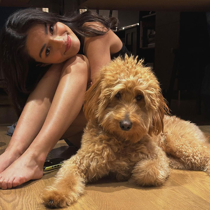 Woman sitting beside a fluffy dog on a wooden floor, looking at the camera. Woman sitting beside a fluffy dog on a wooden floor, looking at the camera.