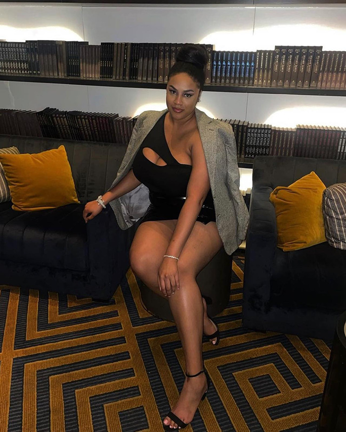 Woman seated stylishly in a lounge, wearing a black dress and blazer, related to stranger braided hair story. Woman seated stylishly in a lounge, wearing a black dress and blazer, related to stranger braided hair story.