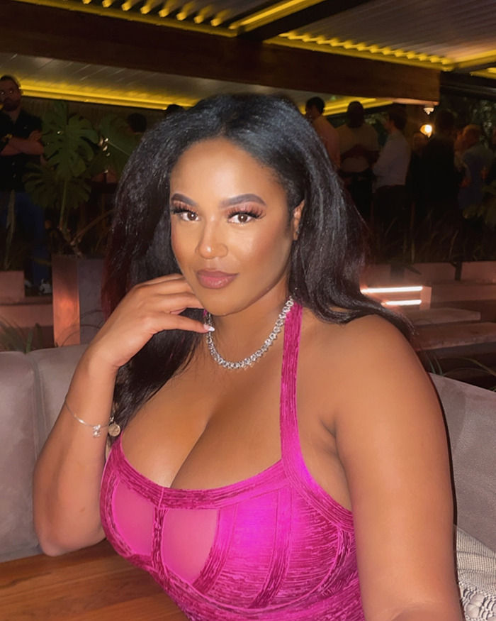 A woman in a pink top seated in a dimly lit restaurant, involved in a viral video story about her hair being braided by a stranger. A woman in a pink top seated in a dimly lit restaurant, involved in a viral video story about her hair being braided by a stranger.