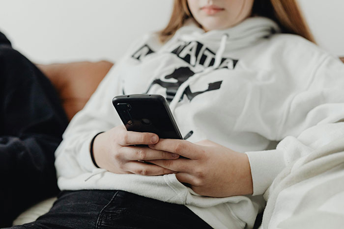 Teen sitting with a phone, wearing a white hoodie, symbolizing entitled behavior issues. Teen sitting with a phone, wearing a white hoodie, symbolizing entitled behavior issues.