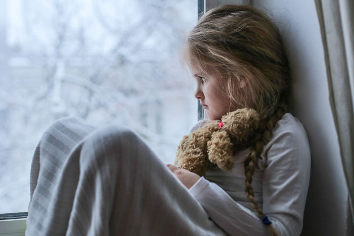 Young girl with leukemia holding a teddy bear, looking out the window, watching for bears every night with sadness. Young girl with leukemia holding a teddy bear, looking out the window, watching for bears every night with sadness.