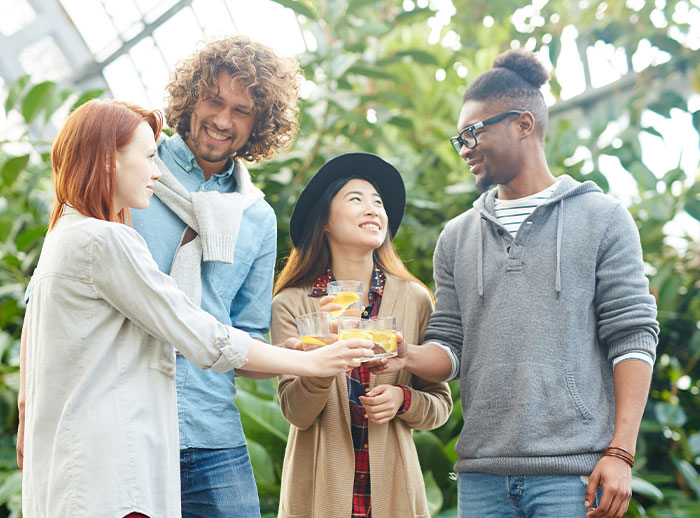 A diverse group of friends enjoying drinks in a garden setting. A diverse group of friends enjoying drinks in a garden setting.
