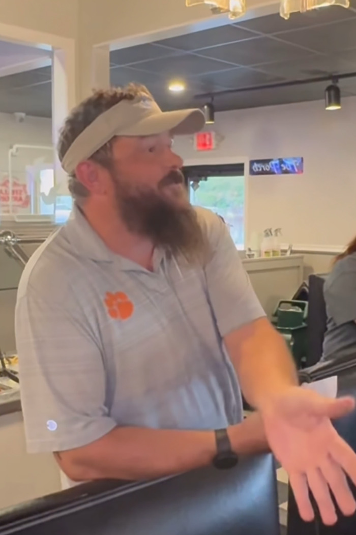Restaurant owner gesturing in frustration during a customer-shaming incident inside a casual dining venue. Restaurant owner gesturing in frustration during a customer-shaming incident inside a casual dining venue.
