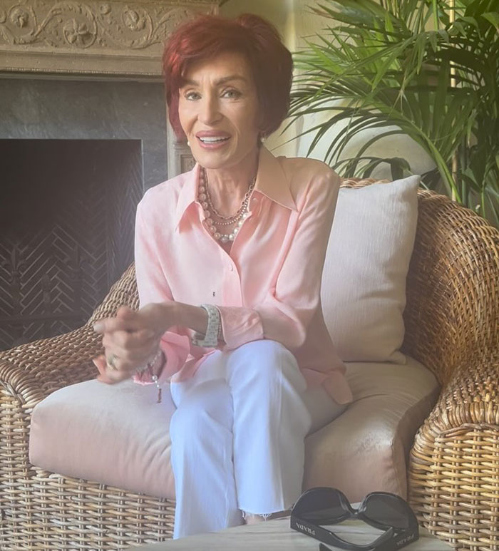 Woman in pink blouse sitting on a wicker chair, with focus on "Ozempic feet" side effect discussion. Woman in pink blouse sitting on a wicker chair, with focus on "Ozempic feet" side effect discussion.