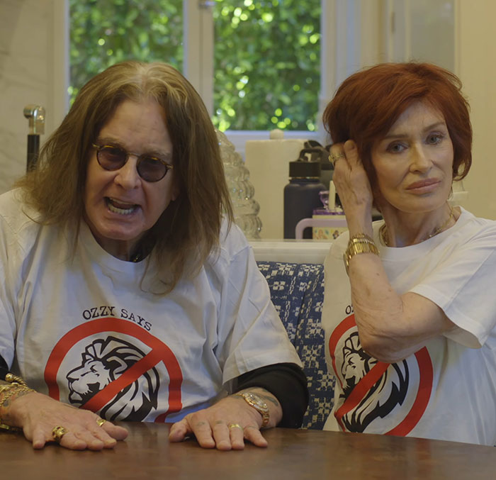 Two people sitting at a table, both wearing matching shirts, inside a well-lit room. Two people sitting at a table, both wearing matching shirts, inside a well-lit room.