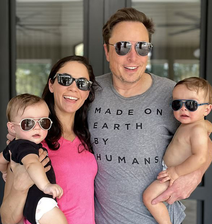 A smiling family with man wearing sunglasses and a "Made on Earth by Humans" shirt, holding babies in sunglasses. A smiling family with man wearing sunglasses and a "Made on Earth by Humans" shirt, holding babies in sunglasses.